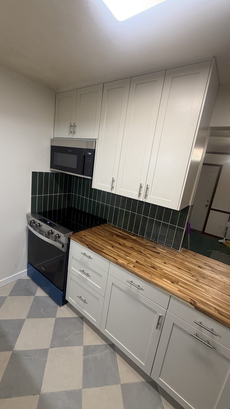 Madison WI kitchen after remodel — white shaker cabinets, butcher-block counter, and green tile backsplash