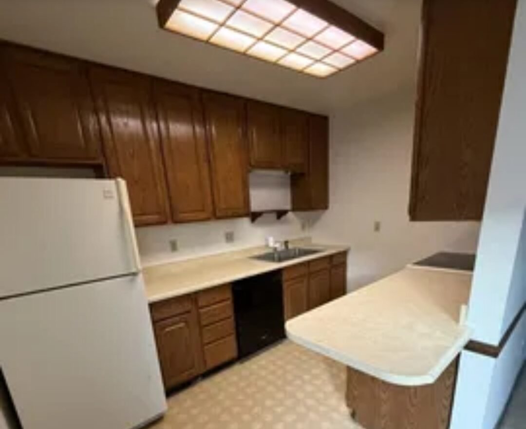 Kitchen before remodel in Madison, WI — dated wood cabinets, laminate counters, and older flooring